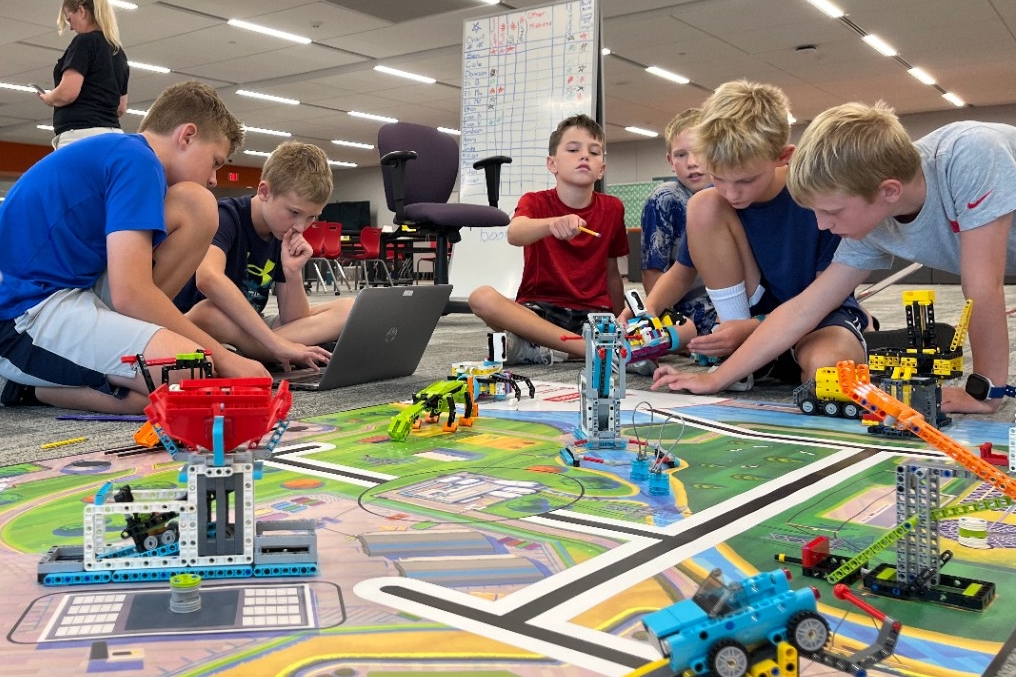 Young kids using elementary programming software to build and code a moving LEGO robot