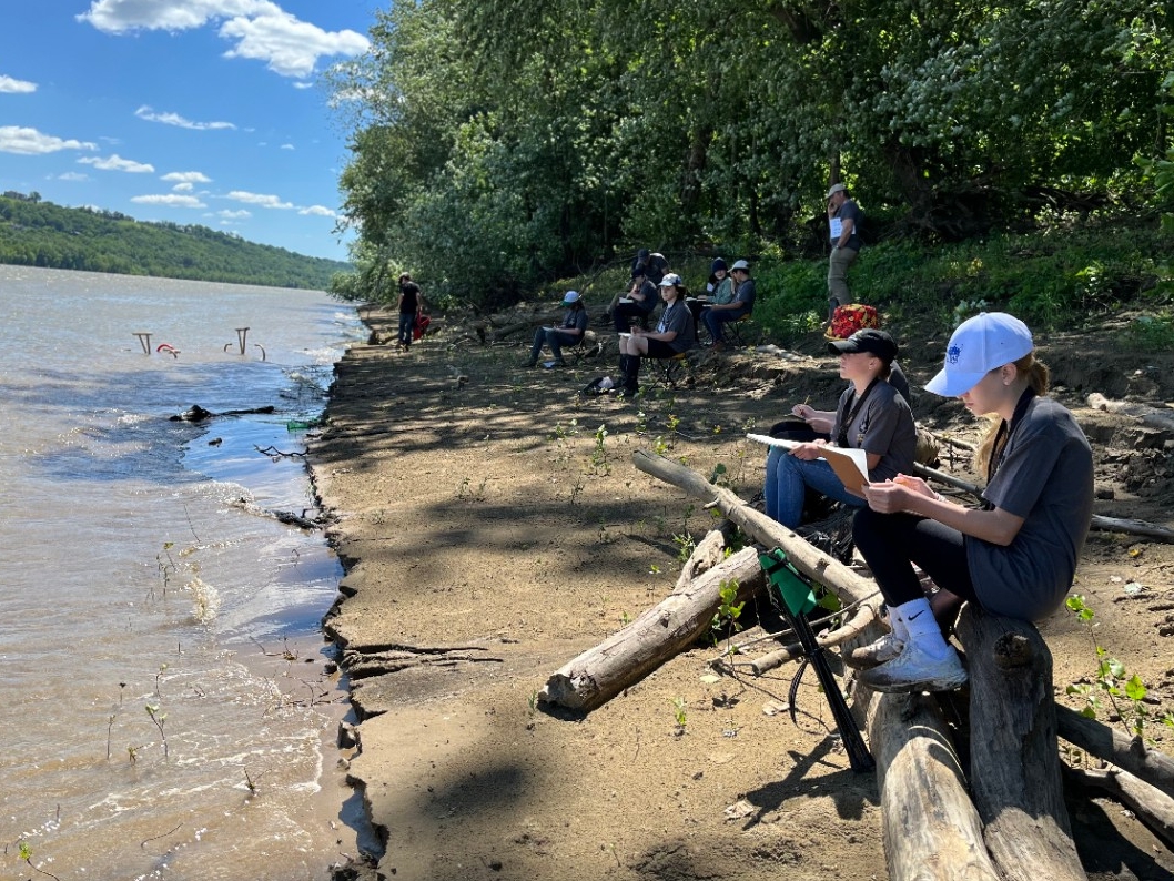 Teens writing and drawing along the banks of the Ohio River