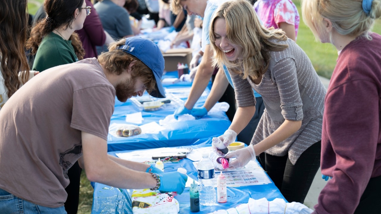 Immerse yourself in NKU's STEM community. NKU STEM majors smiling and laughing while making custom tie-dye shirts outside on a sunny day.