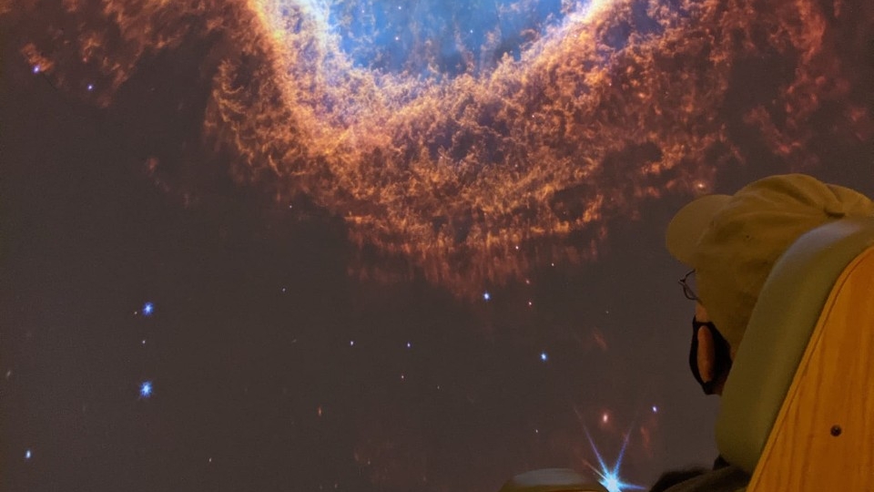 A planetarium visitor gazes at a galaxy filled screen.