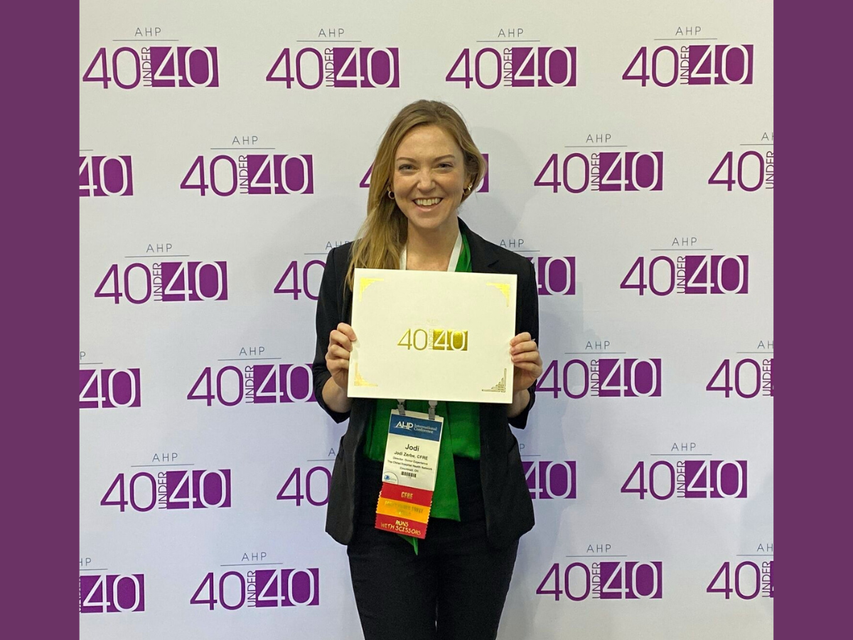Jodi Zerbe holding certificate in front of 40 under 40 backdrop