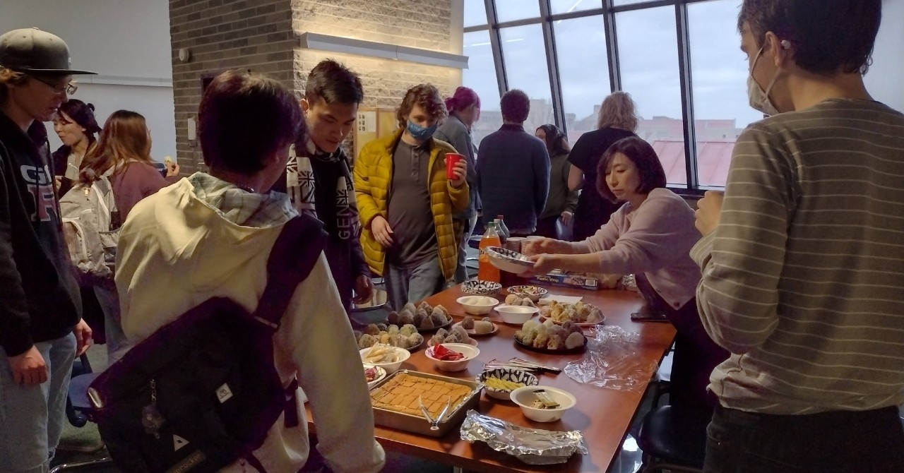 Students gathered around a table with Japanese food.
