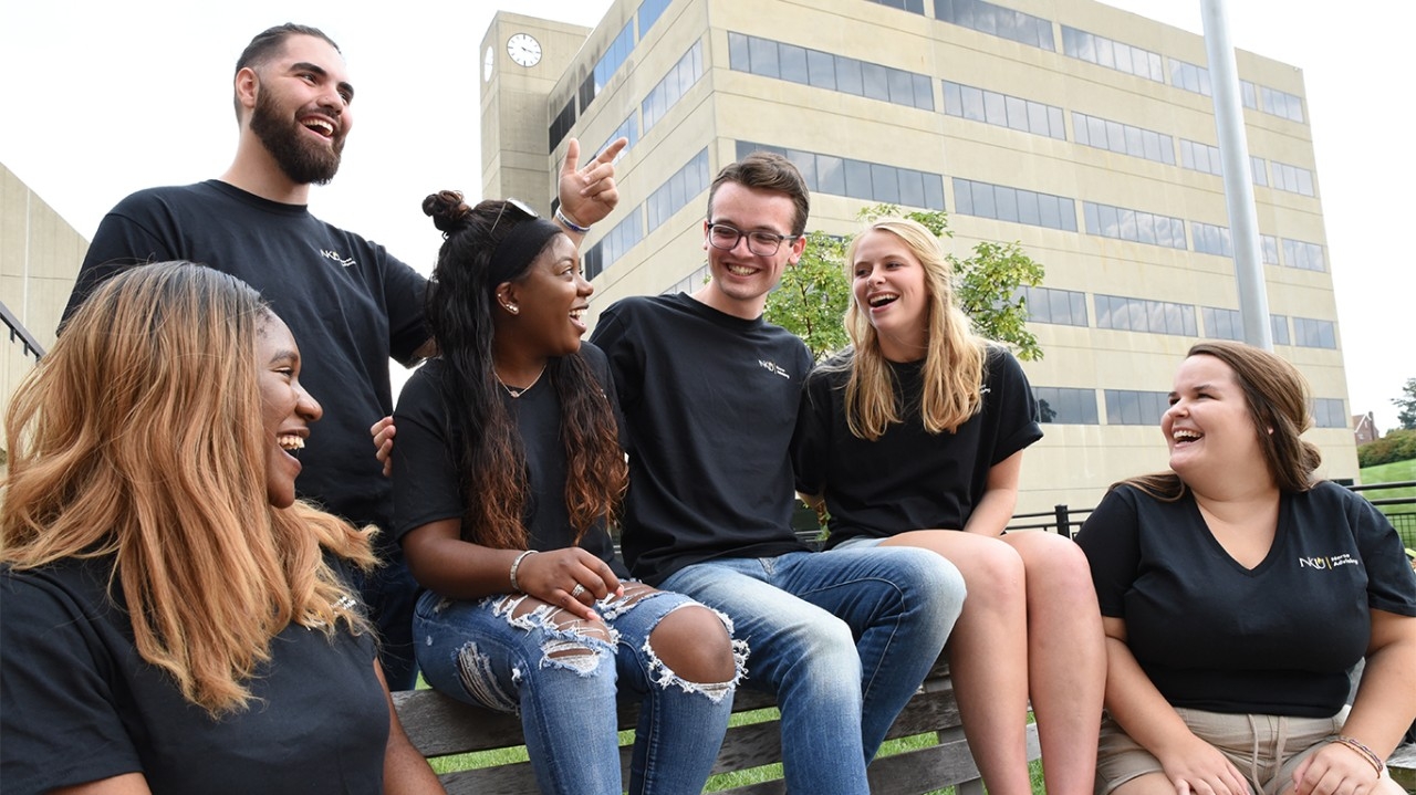Group of students sitting on a bench outside of the Lucas Administration building