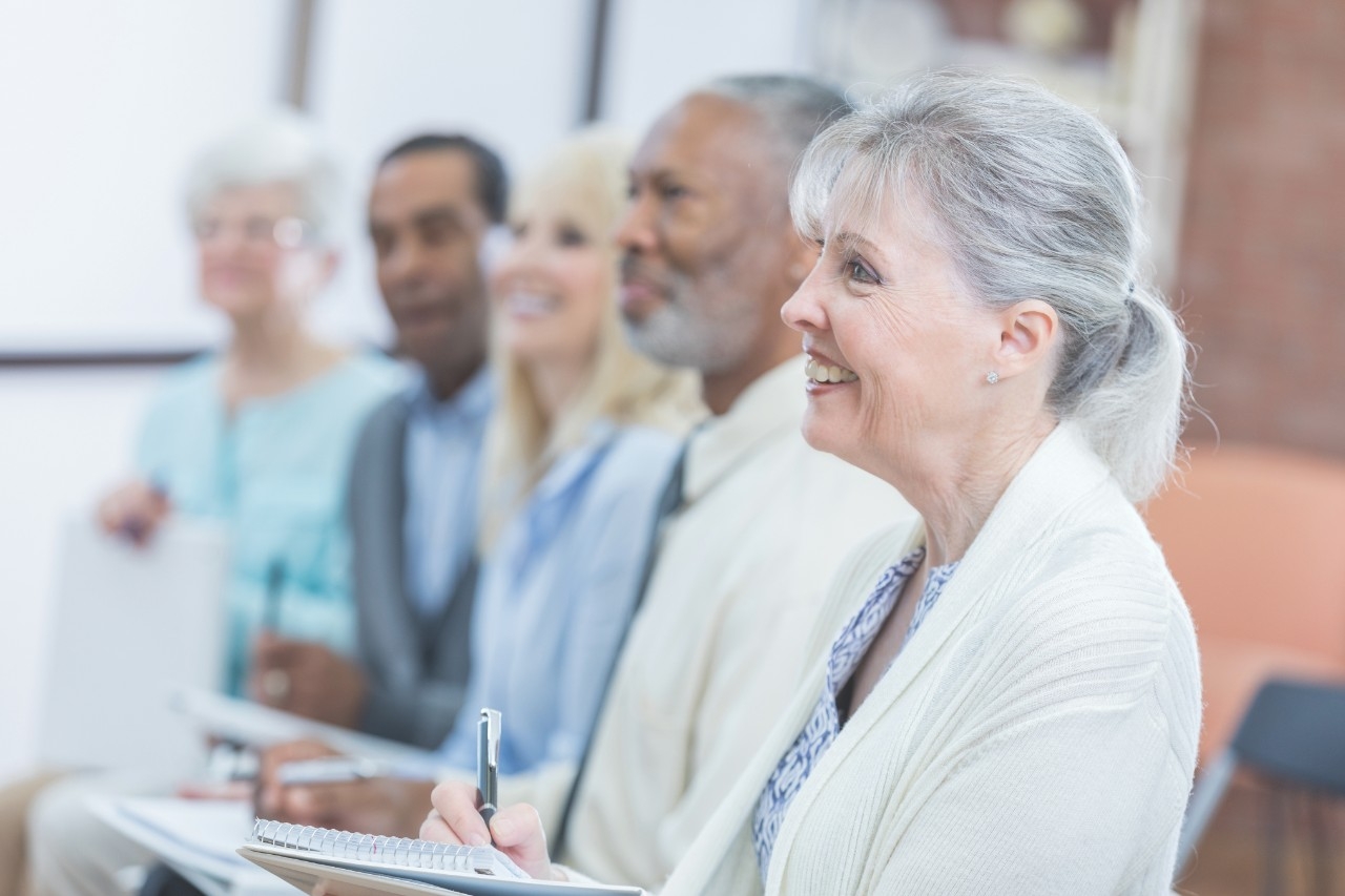 Donovan Scholar Cover Photo Smiling senior Caucasian woman attends a retirement planning seminar with her friends.